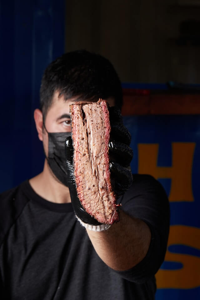 Man holding up brisket and showing its structure inside
